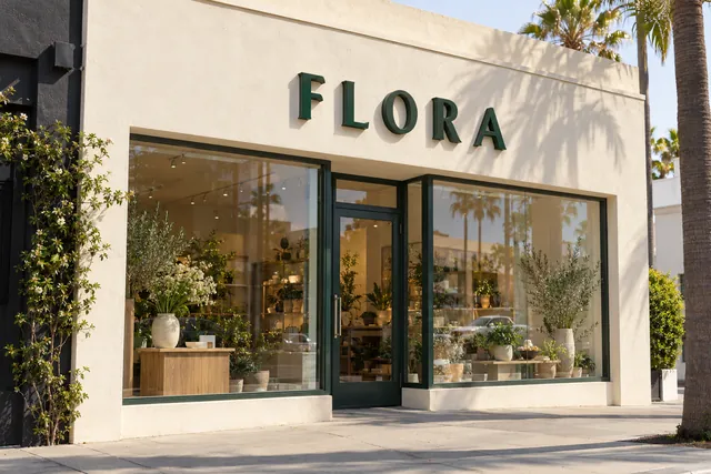 Illustration: painted green dimensional letters spelling FLORA on a flower shop's stucco fascia
