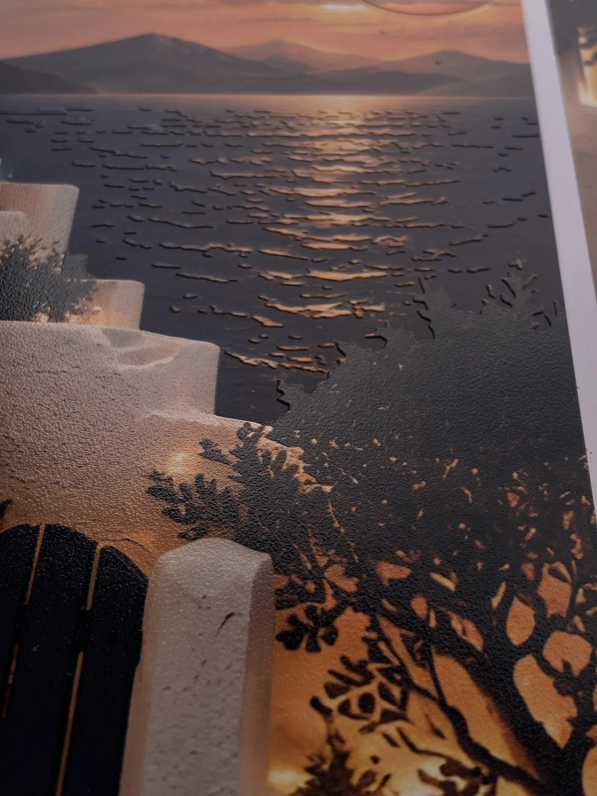 Close-up of a raised UV print of a seaside terrace at sunset, with visible texture on the water